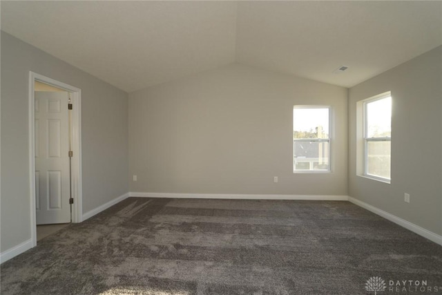 empty room featuring baseboards, dark carpet, and vaulted ceiling