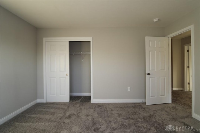 unfurnished bedroom with a closet, dark carpet, and baseboards