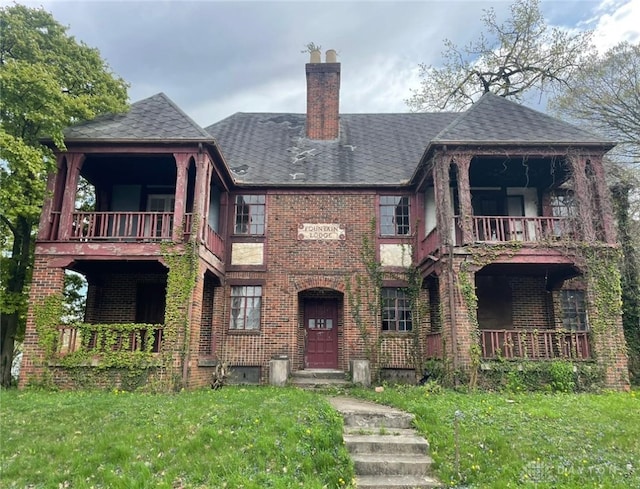 view of front of home with a balcony and a front lawn