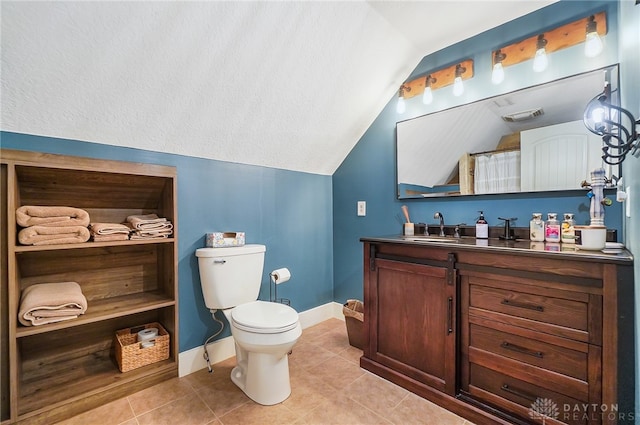 bathroom with tile patterned flooring, vanity, toilet, and vaulted ceiling