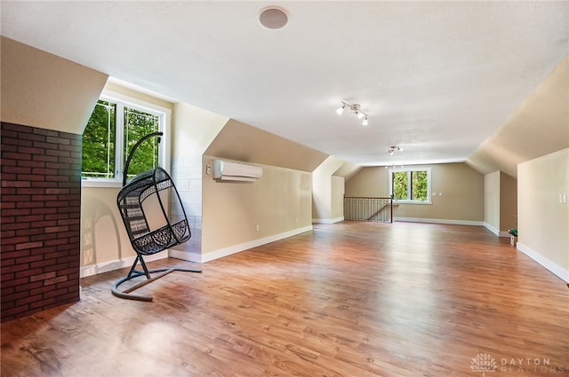 bonus room with a wall unit AC, a wealth of natural light, vaulted ceiling, and light hardwood / wood-style floors