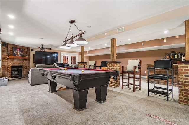 rec room with a brick fireplace, french doors, light colored carpet, billiards, and ceiling fan