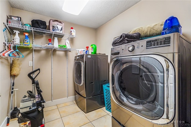 laundry area featuring a textured ceiling, independent washer and dryer, and light tile patterned flooring