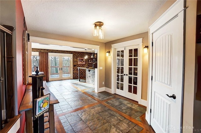 interior space with a textured ceiling, brick wall, and french doors