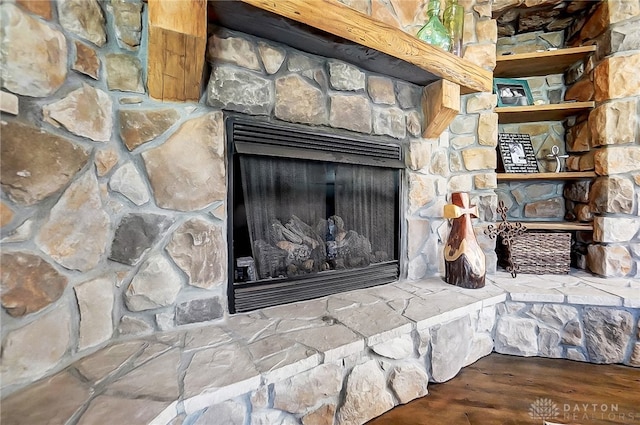 room details featuring a stone fireplace and wood-type flooring