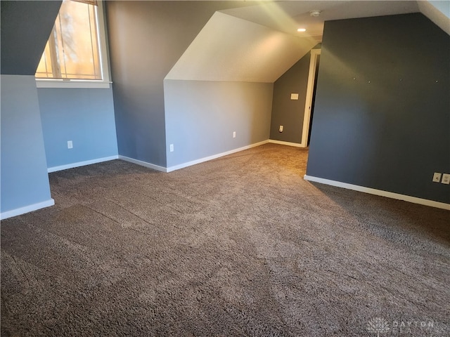 additional living space with dark colored carpet and lofted ceiling