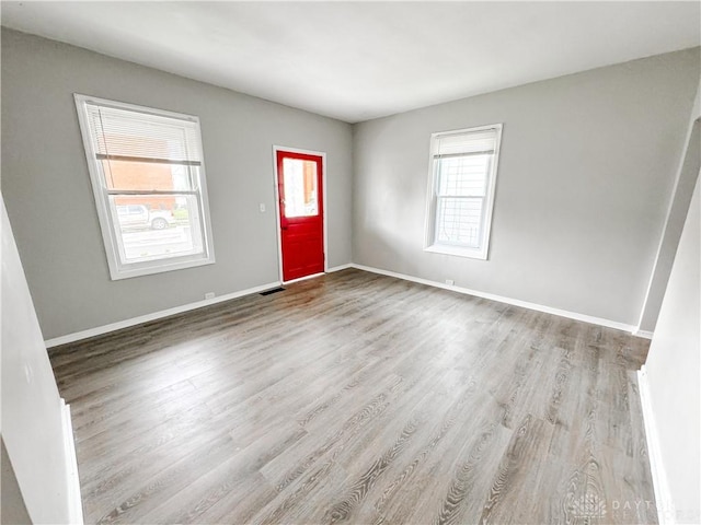 foyer with baseboards, visible vents, and wood finished floors