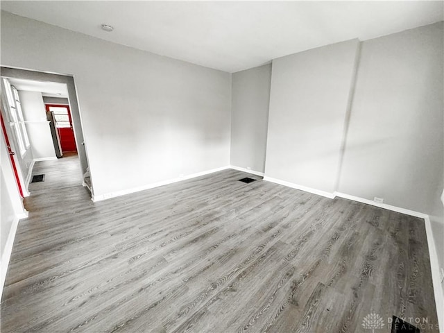 unfurnished room featuring baseboards, wood finished floors, and visible vents