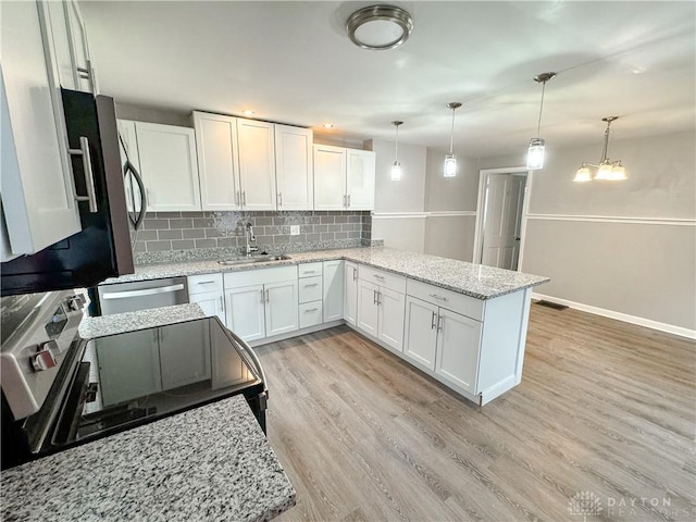 kitchen with decorative backsplash, a sink, baseboards, white cabinets, and light wood finished floors