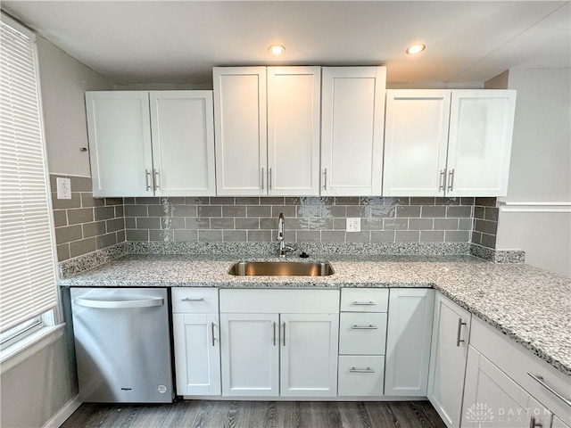 kitchen with white cabinets, dark wood-style flooring, light stone counters, a sink, and dishwasher