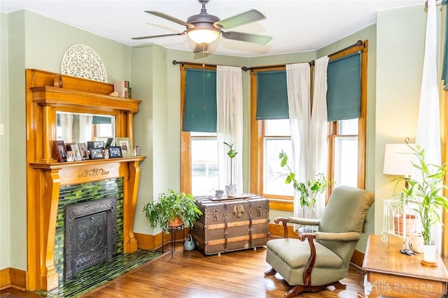 sitting room featuring ceiling fan, a fireplace, and wood finished floors