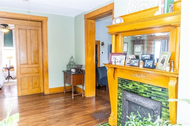 interior space featuring a tile fireplace, visible vents, baseboards, and wood finished floors