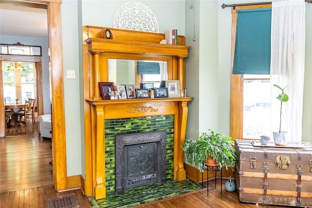 living area featuring baseboards, visible vents, wood finished floors, and a tile fireplace