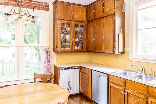 kitchen with a sink, a wealth of natural light, brown cabinetry, and dishwasher