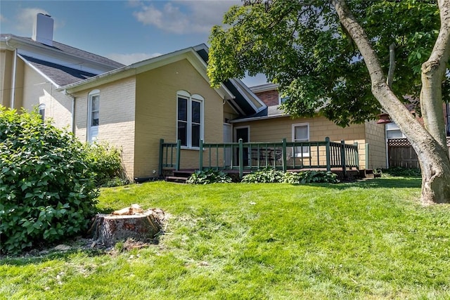 rear view of house with a yard, a wooden deck, and brick siding