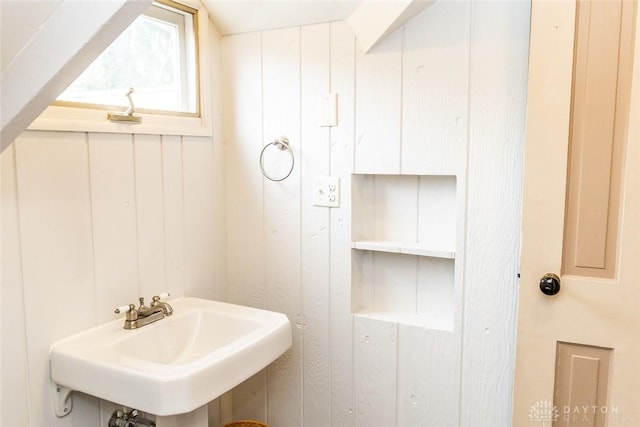 bathroom featuring a sink and wooden walls