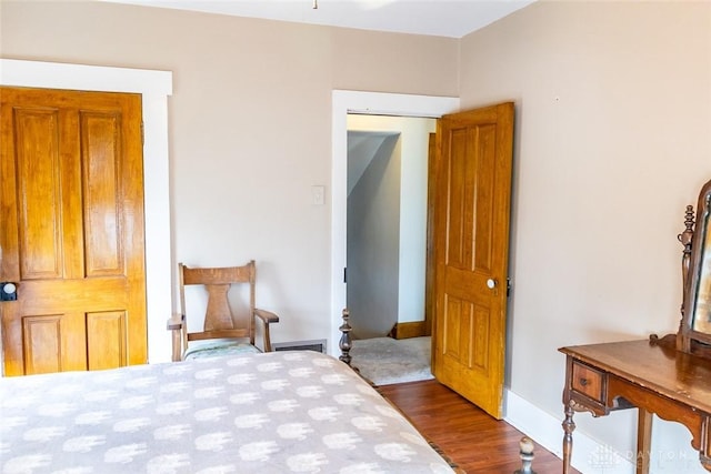 bedroom with dark wood-type flooring and baseboards