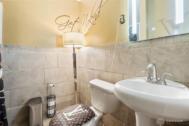 bathroom with sink, tile walls, and toilet