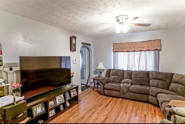 living room featuring a textured ceiling, ceiling fan, and light hardwood / wood-style floors