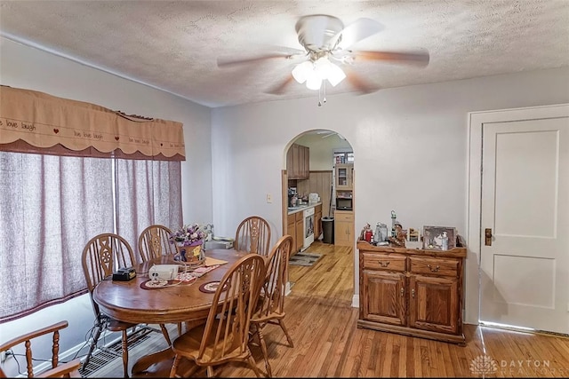 dining area with light hardwood / wood-style floors, a textured ceiling, and ceiling fan