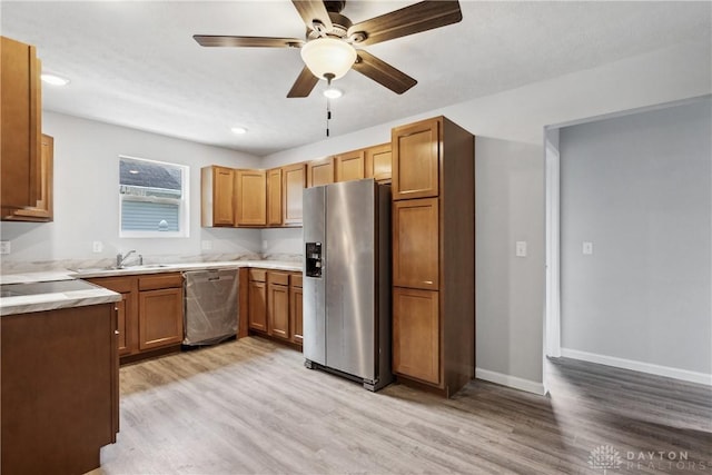 kitchen with brown cabinets, light wood-type flooring, appliances with stainless steel finishes, and light countertops