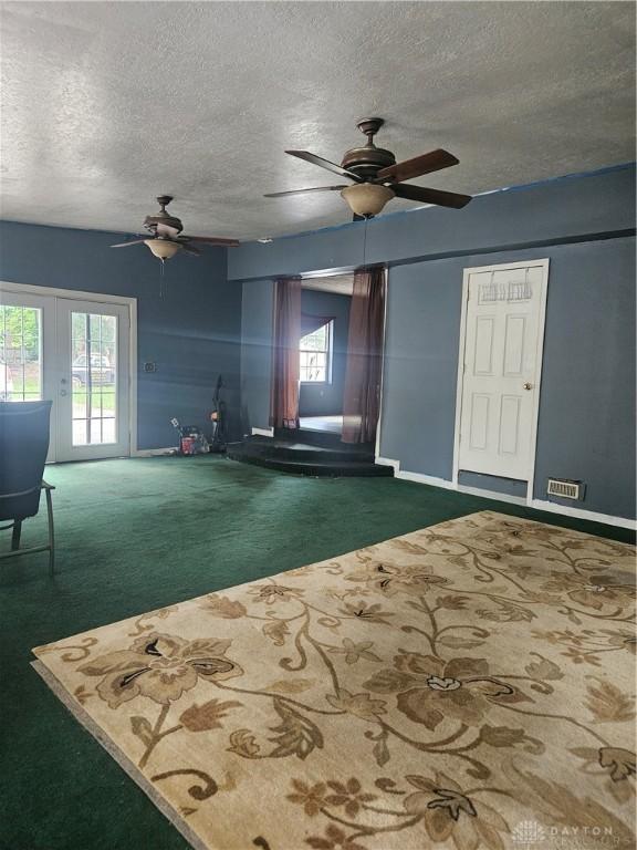 unfurnished living room featuring a ceiling fan, carpet floors, baseboards, and a textured ceiling