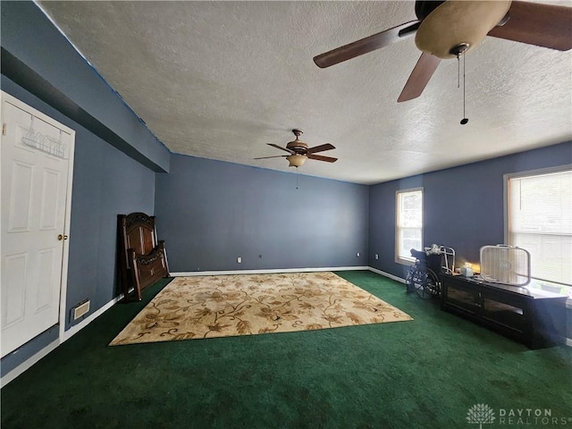 unfurnished living room featuring baseboards, dark carpet, ceiling fan, and a textured ceiling