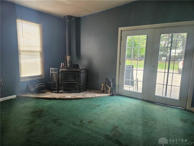 living room with a wood stove, french doors, vaulted ceiling, and carpet floors