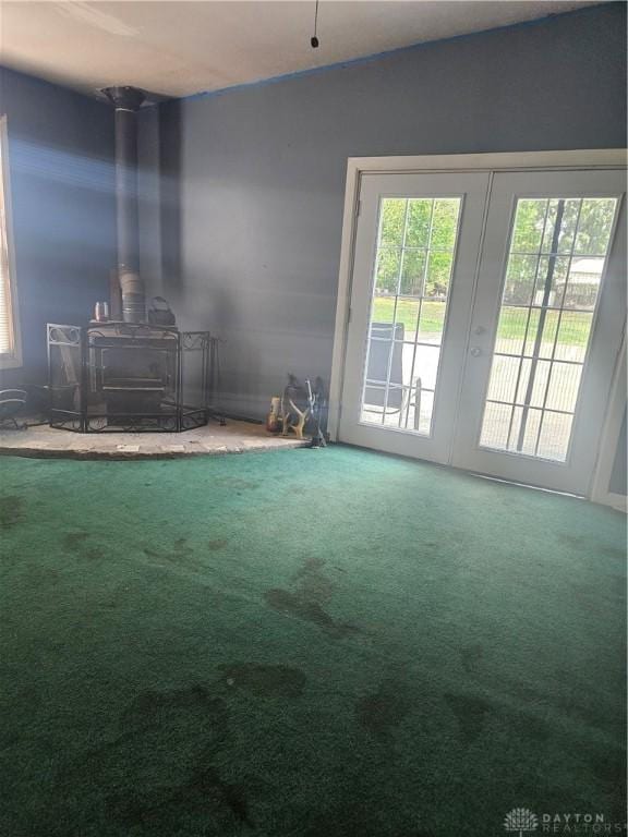 unfurnished living room featuring vaulted ceiling, carpet flooring, and a wood stove