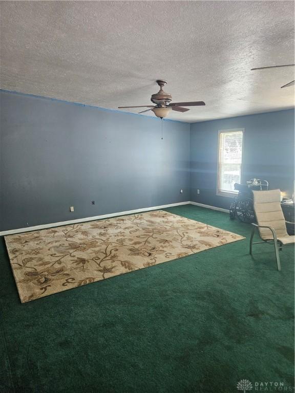 carpeted spare room featuring baseboards, ceiling fan, and a textured ceiling