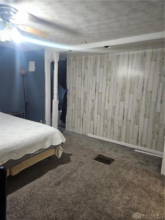 unfurnished bedroom featuring visible vents, a textured ceiling, and carpet floors