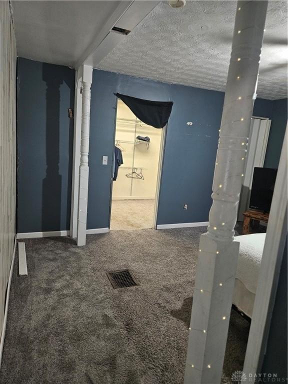 carpeted spare room with baseboards, visible vents, and a textured ceiling