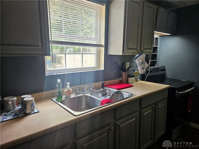 kitchen with light countertops, electric range oven, and a sink