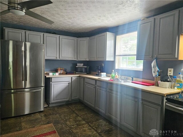 kitchen featuring gray cabinets, stainless steel refrigerator, dark tile patterned floors, and ceiling fan