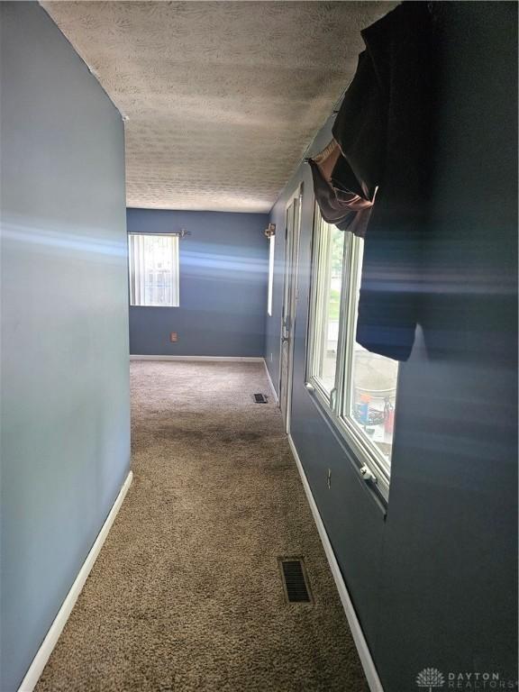 hallway with carpet and a textured ceiling