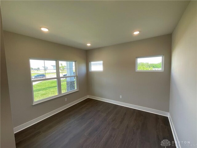 unfurnished room featuring dark wood-type flooring and plenty of natural light