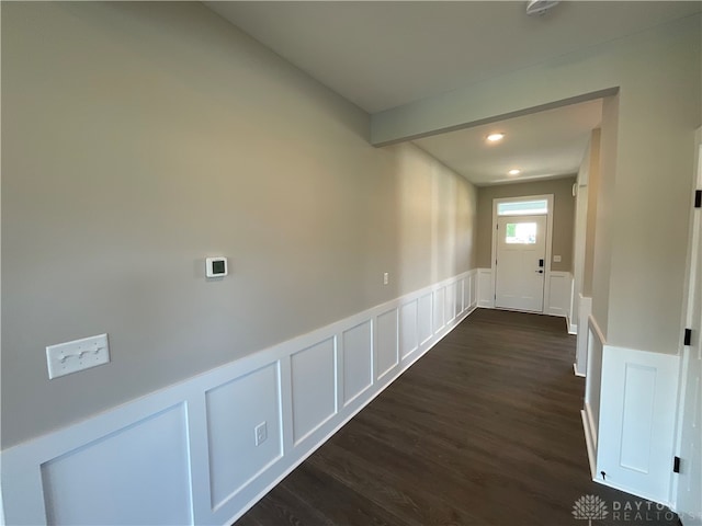 corridor featuring dark wood-type flooring and beam ceiling