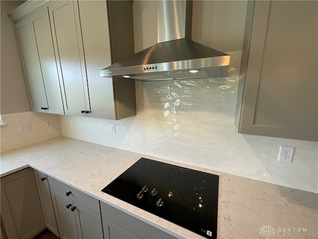 kitchen featuring gray cabinets, decorative backsplash, wall chimney range hood, and black electric cooktop