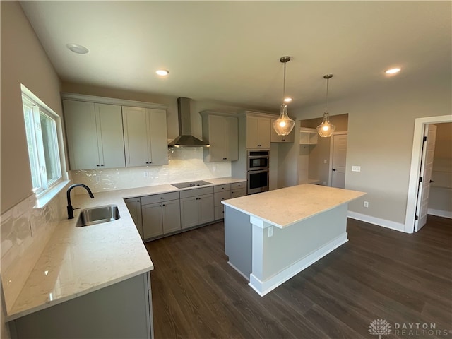 kitchen featuring sink, a kitchen island, wall chimney exhaust hood, pendant lighting, and dark hardwood / wood-style floors