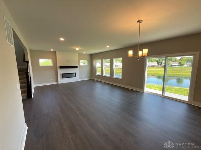 unfurnished living room featuring dark hardwood / wood-style flooring, a water view, and plenty of natural light