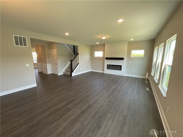 unfurnished living room with a large fireplace and dark wood-type flooring