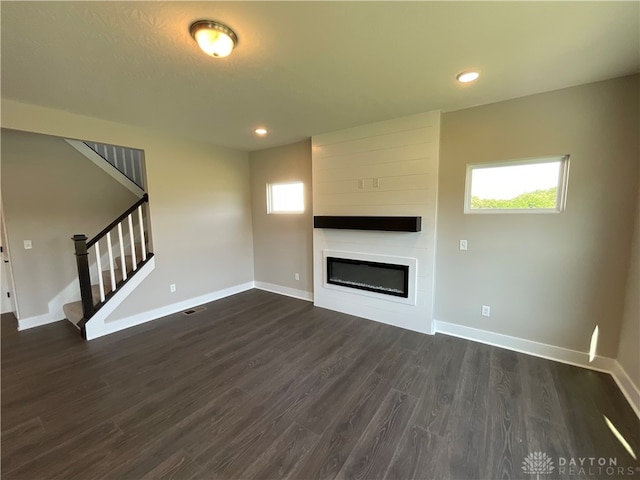 unfurnished living room with a textured ceiling, a large fireplace, and dark wood-type flooring