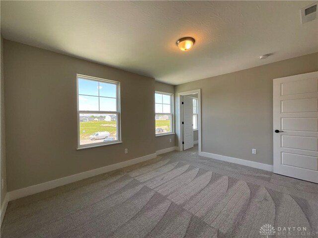 empty room featuring a textured ceiling and light colored carpet