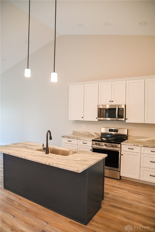 kitchen featuring a kitchen island with sink, light hardwood / wood-style flooring, hanging light fixtures, stainless steel appliances, and white cabinets