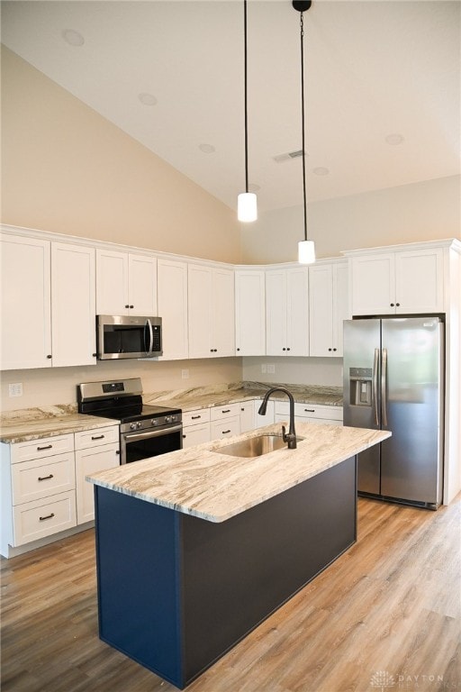 kitchen featuring sink, hanging light fixtures, stainless steel appliances, light hardwood / wood-style flooring, and a kitchen island with sink