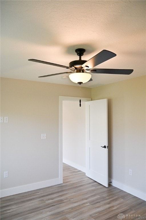 unfurnished room with ceiling fan, wood-type flooring, and a textured ceiling