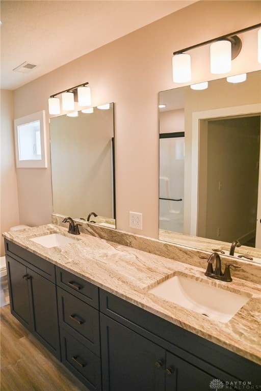 bathroom with vanity, hardwood / wood-style flooring, walk in shower, and toilet