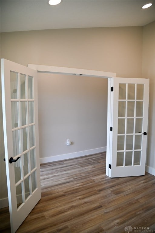 empty room with lofted ceiling, french doors, and dark hardwood / wood-style flooring