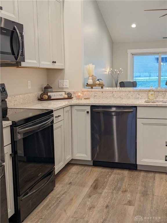 kitchen with appliances with stainless steel finishes, light hardwood / wood-style flooring, light stone counters, and sink