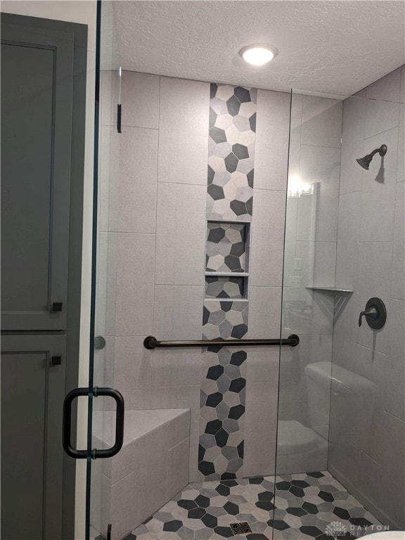 bathroom featuring a shower with door and a textured ceiling